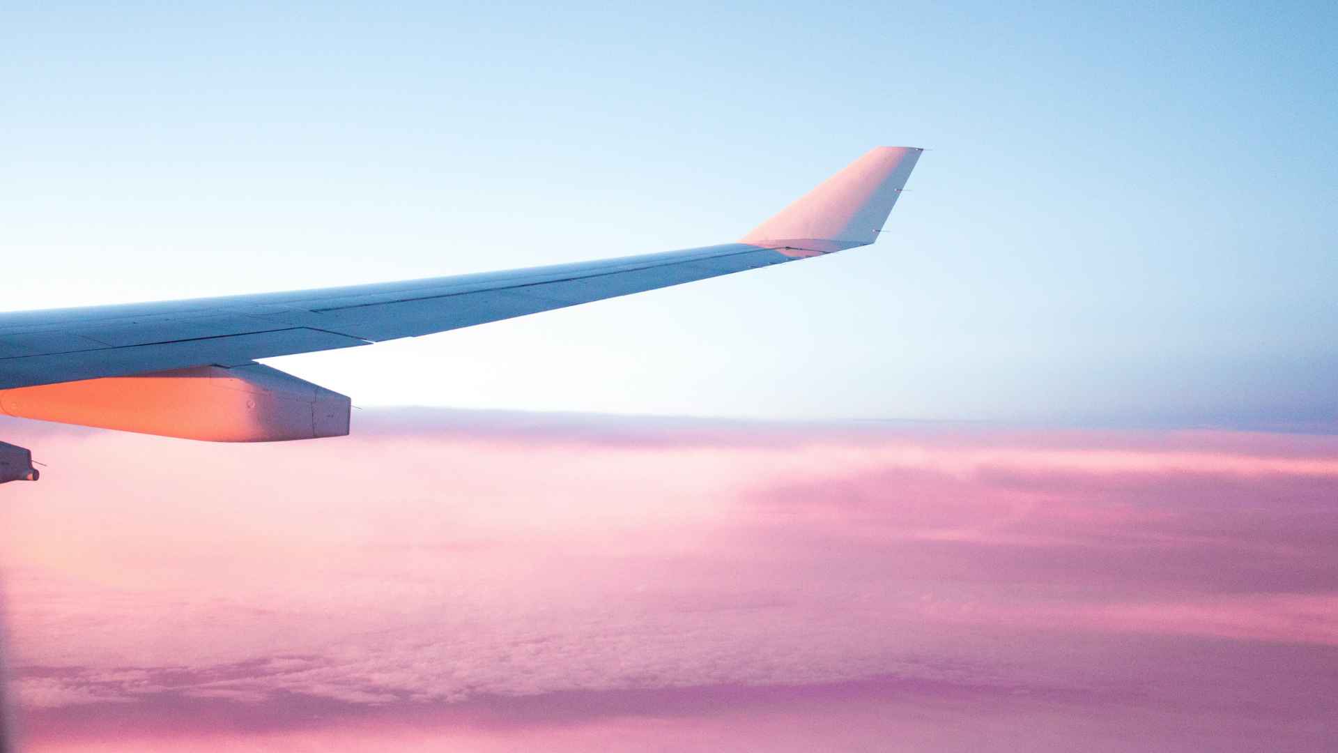 ottimizzare-il-rispermio Ala di un aereo su nuvole rosa, metafora per risparmiare per realizzare i desideri