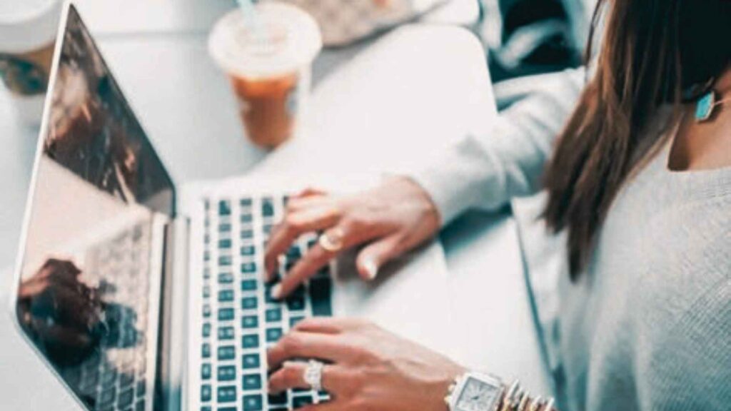 primo piano sulle mani di una donna che scrive al portatile compilando il file per il controllo di gestione della sua attività